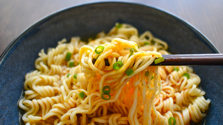 Instant noodles being picked up out of bowl with chopsticks
