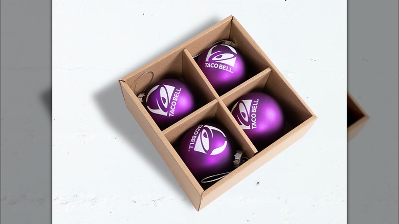 A box of four round purple ornaments with the Taco Bel logo