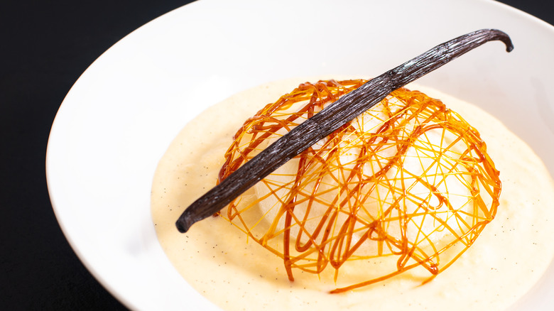 An île flottante dessert with a long vanilla bean balanced overtop