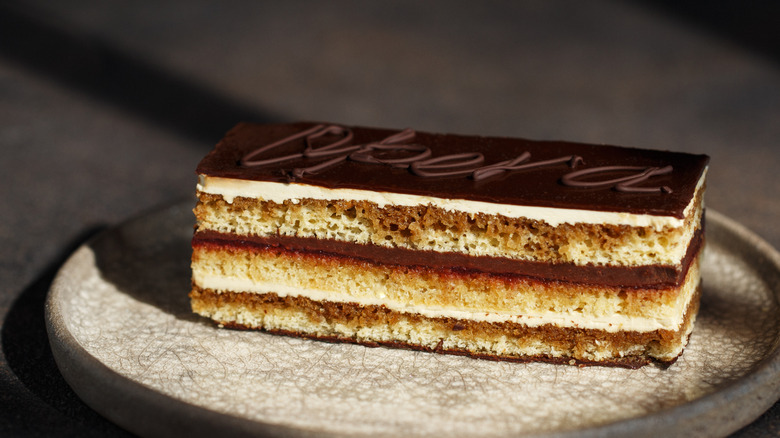 A slice of opera cake with the word opera written in chocolate across the top