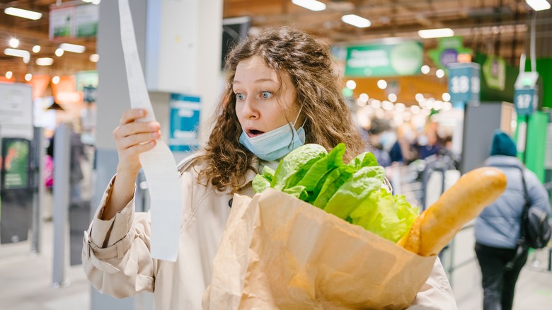 Woman shocked looking at grocery store receipt 