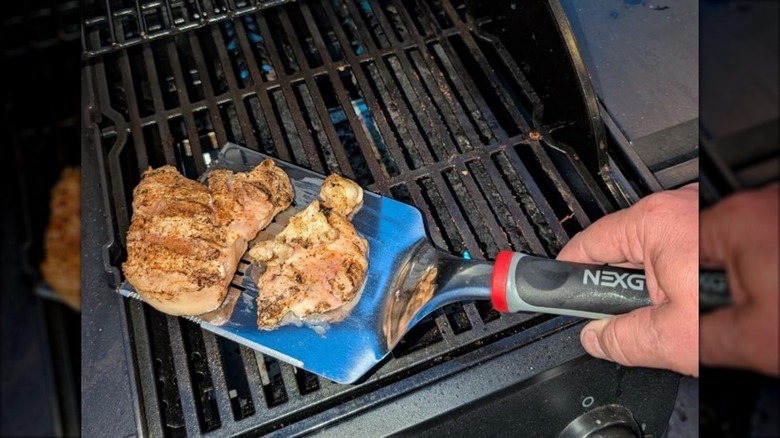 Nexgrill Daytona stainless steel griddle spatula being used to flip grilled meat