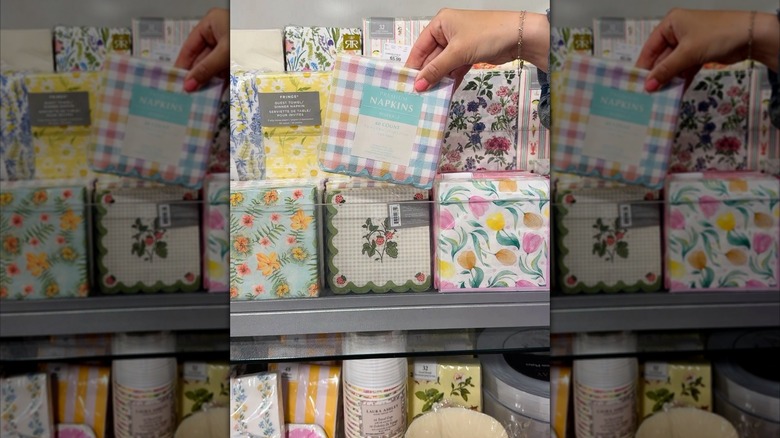 A hand picking out a package of napkins from an array of different styles
