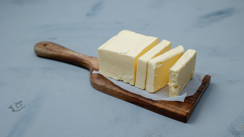 Sliced stick of butter on wooden board