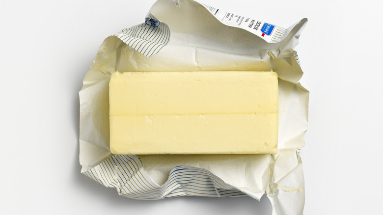 Unwrapped stick of butter in its paper