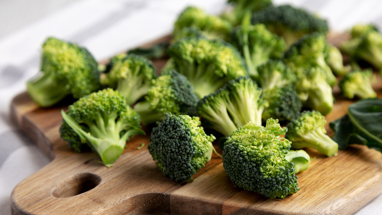 Raw broccoli florets on wooden board