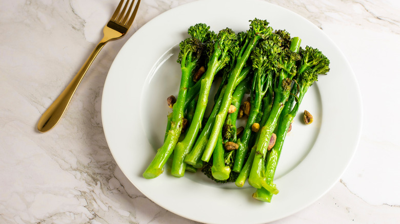 Plate of roasted broccolini, with golden fork sitting next to it