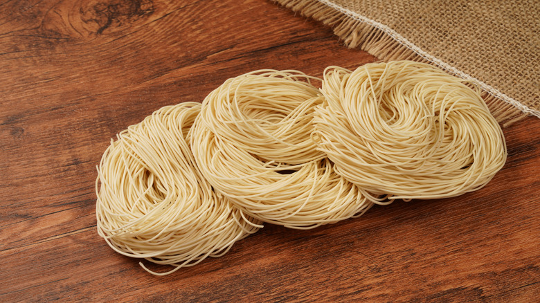 Stack of raw noodle nests on wooden table