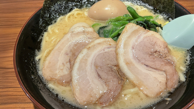 Bowl of tonkotsu-style ramen, with three thick slices of pork belly and a marinated egg