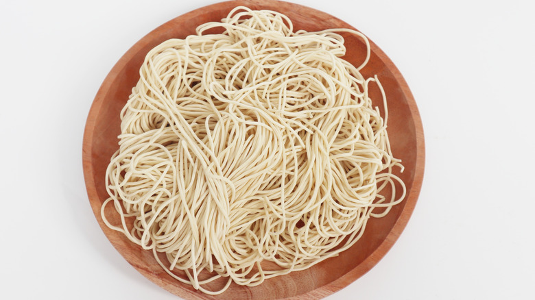 Raw ramen noodles in brown wooden bowl