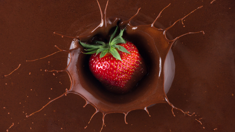 Strawberry falling into melted chocolate