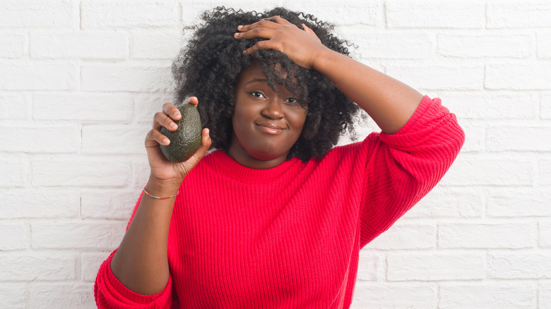 woman holding avocado
