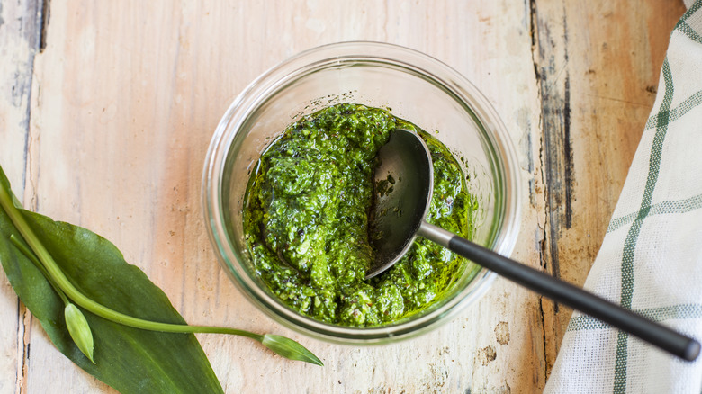 glass bowl of homemade pesto with metal spoon