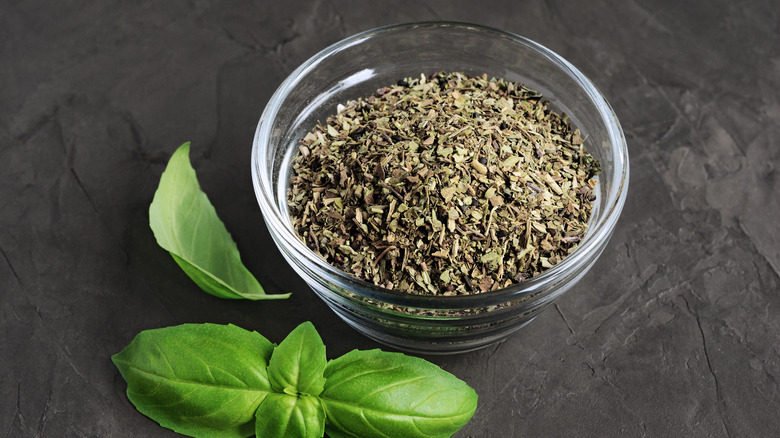 dried basil in bowl with fresh basil leaves next to it