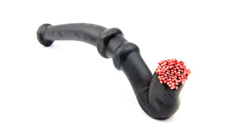Piece of black licorice shaped like tobacco pipe, with red nonpareils on end