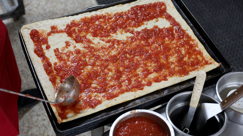 Spreading sauce on pizza