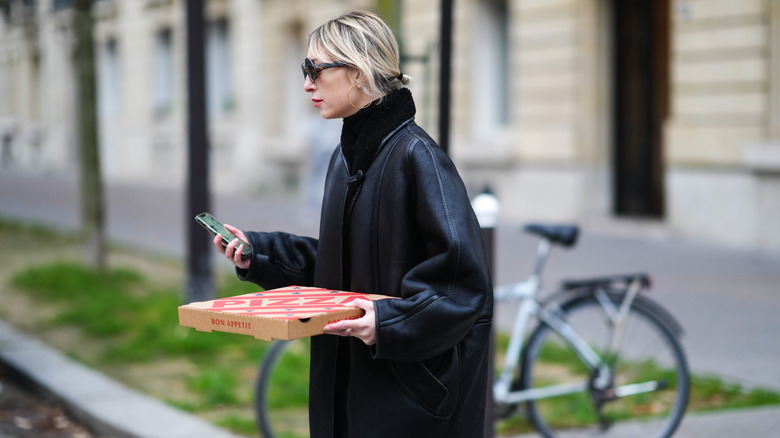 Woman carrying takeout pizza