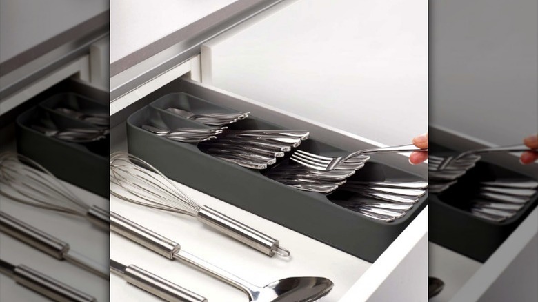 Compact cutlery tray in drawer with hand putting a fork in