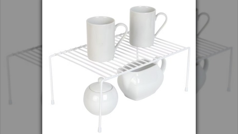 Metal shelf rack with cups on white background