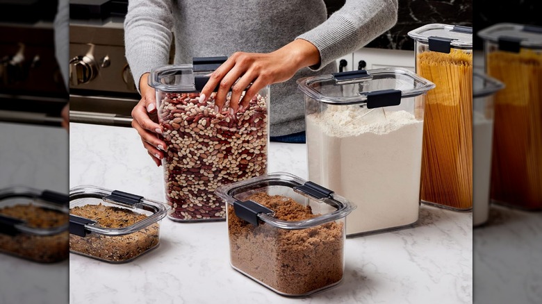 A hand closing a Rubbermaid Brilliance airtight pantry container on a countertop