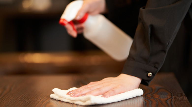 hands cleaning table with rag