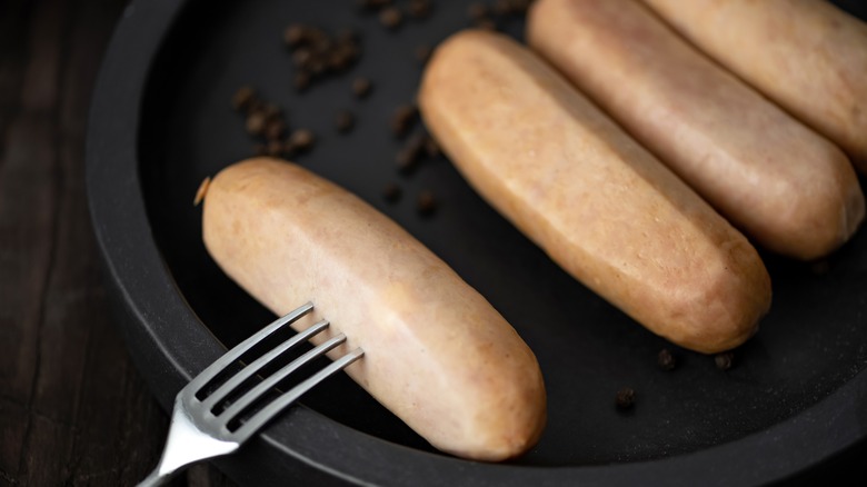 raw sausages with a fork