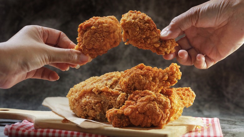 people holding up fried chicken legs