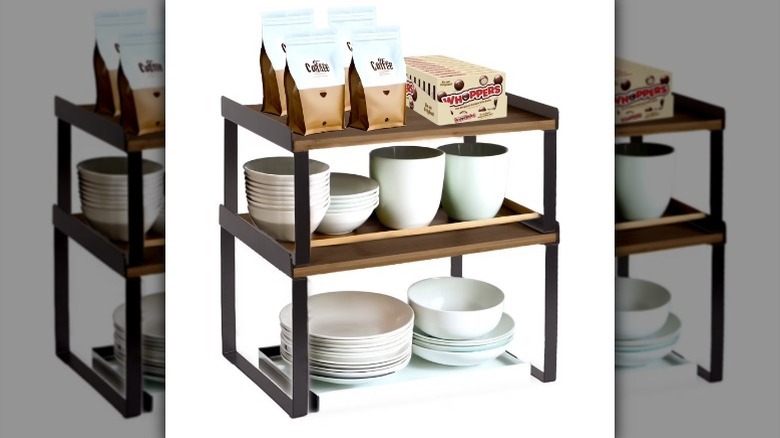 Tiered shelf with kitchen items like coffee mugs, plates, and coffee bags on white background