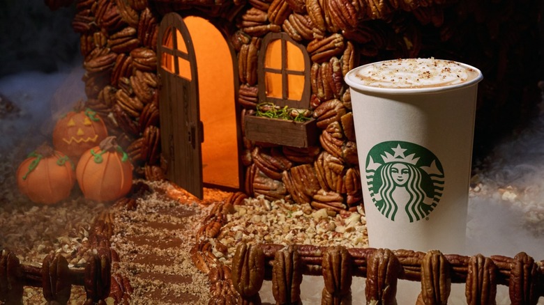 Starbucks' pecan crunch oatmilk latte in a spooky setting with a house and fence made of pecans