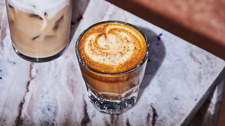 Glass of Starbucks' pecan oatmilk cortado on a white-marbled table