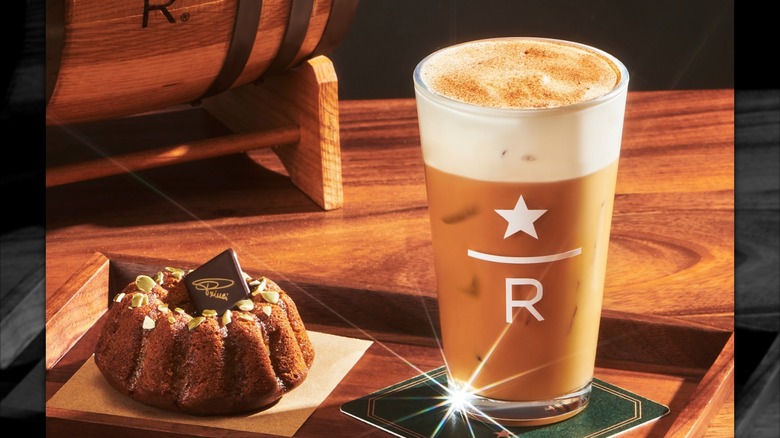 Glass of Starbucks Reserve pumpkin spice whiskey barrel-aged cold brew in a serving tray with pumpkin spice cake