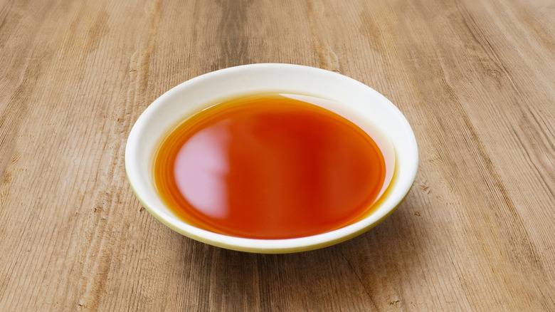 A white bowl on a table contains fish sauce.