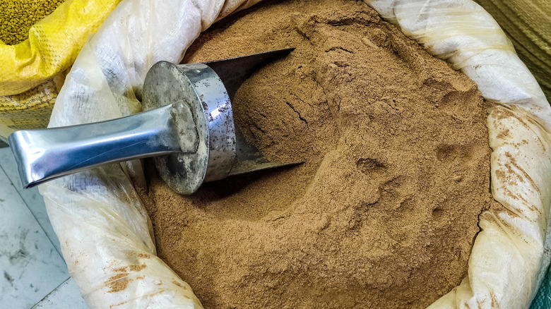 A sack of garam masala is displayed with a scoop in it.