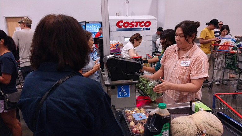 Costco cashier scanning customer's items, with various customers in the background