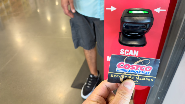 Person holding Costco Executive Member card in front of scanning machine