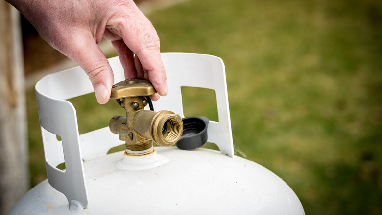 person turning propane tank valve