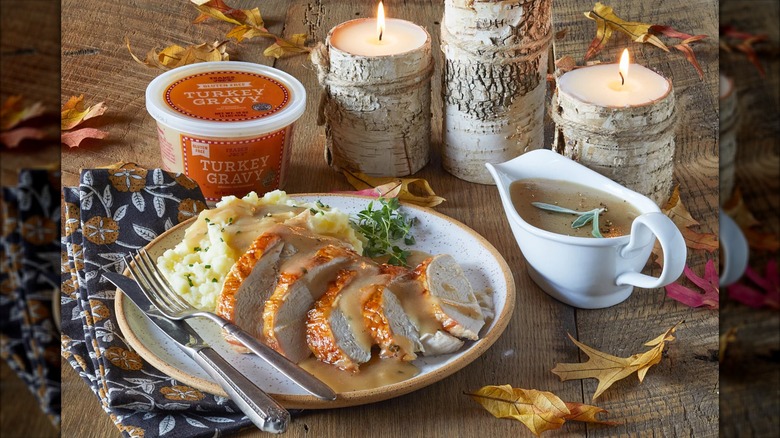 Trader Joe's gluten free turkey gravy in a gravy boat and retail container, poured over turkey and potatoes