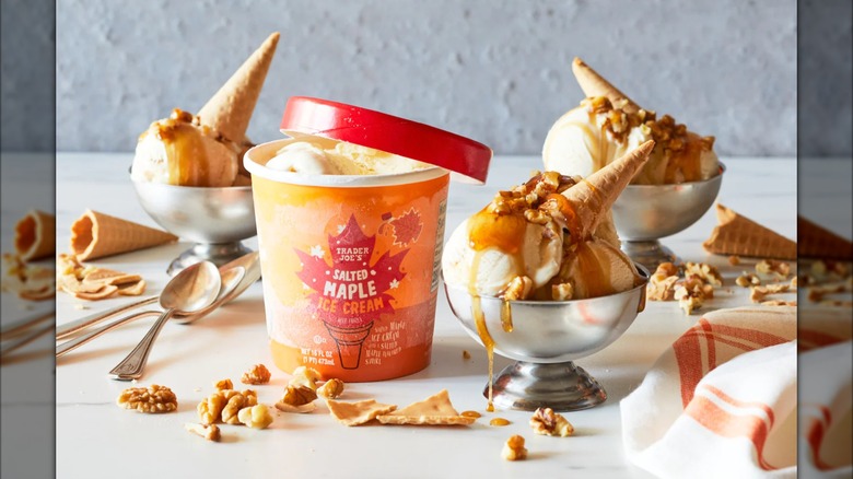A tub of Trader Joe's salted maple ice cream next to bowls of the same, with waffle cones sticking out