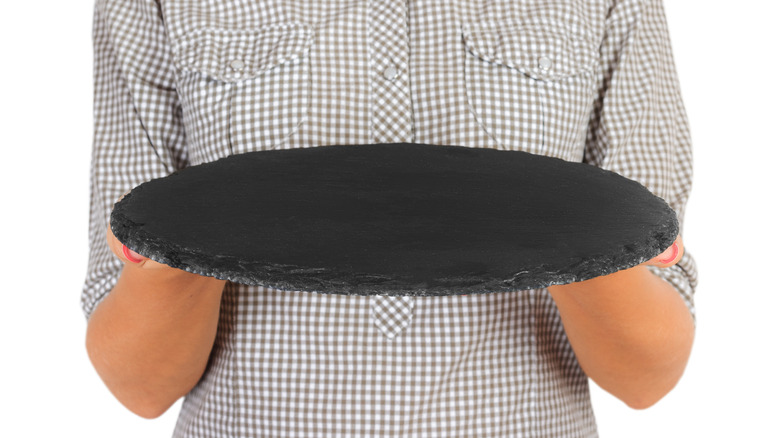 Person holding a pizza stone