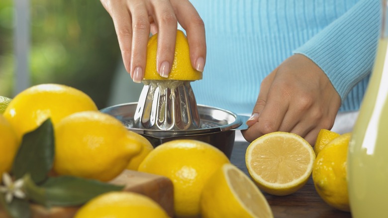 Closeup of woman in blue shirt juicing lemons