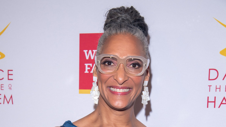 Carla Hall, grinning and wearing a pair of thick-rimmed flasses