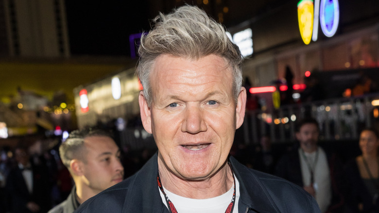 Street photograph of Gordon Ramsay at night, with city lights behind him