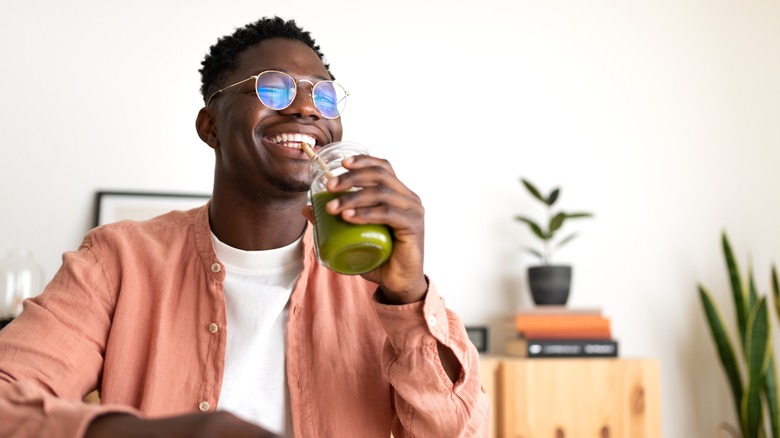 man drinking green smoothie