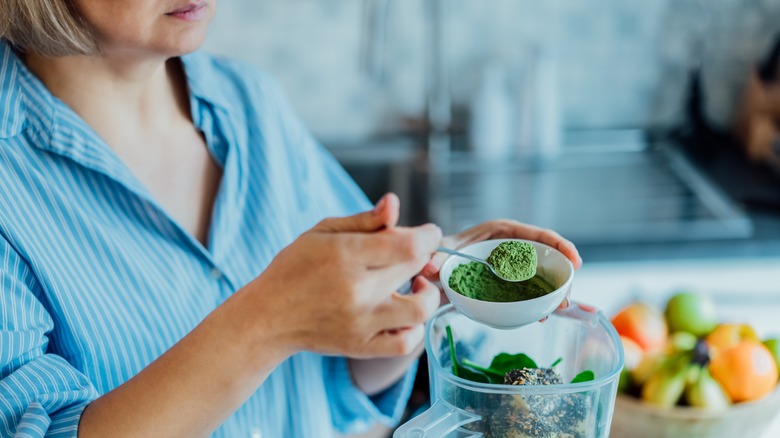 scooping green powder into blender