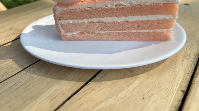 Slice of lychee cake, with buttercream layers, topped with a fresh lychee and berries
