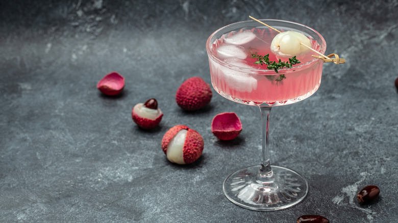 Lychee soda in a high-stem glass, with fresh lychees around it