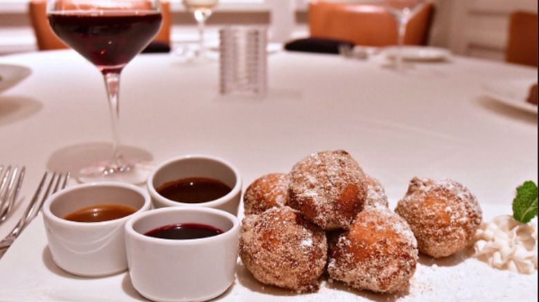 Zeppole Dessert From The Palm with dipping sauces and wine glass