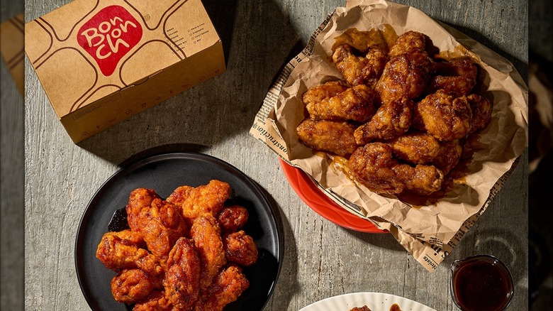 Two flavors of Bonchon wings with a drink and logoed to-go box