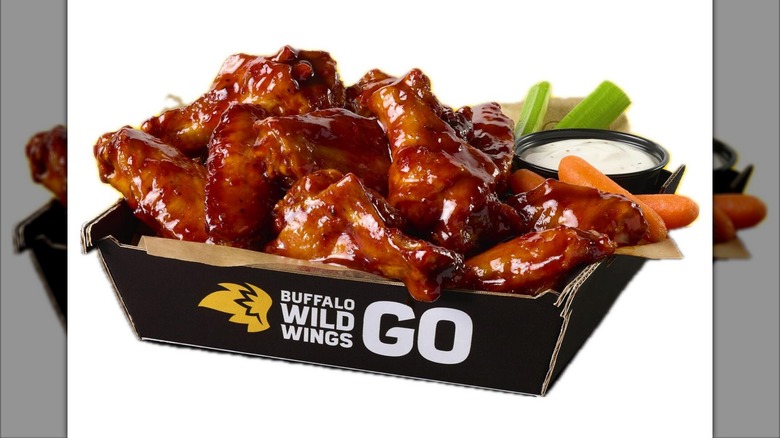 Buffalo Wild Wings GO to-go box full of saucy wings with celery and dipping sauce