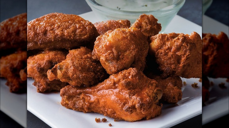 Marco's Pizza wings on a white plate with a ramekin of dipping sauce